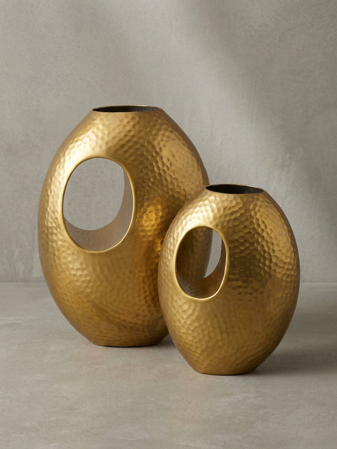 Frontansicht des zweiteiligen Deko-Vasen-Sets aus Aluminium in Gold mit markanter Hammerschlag-Optik, freigestellt vor weißem Hintergrund._