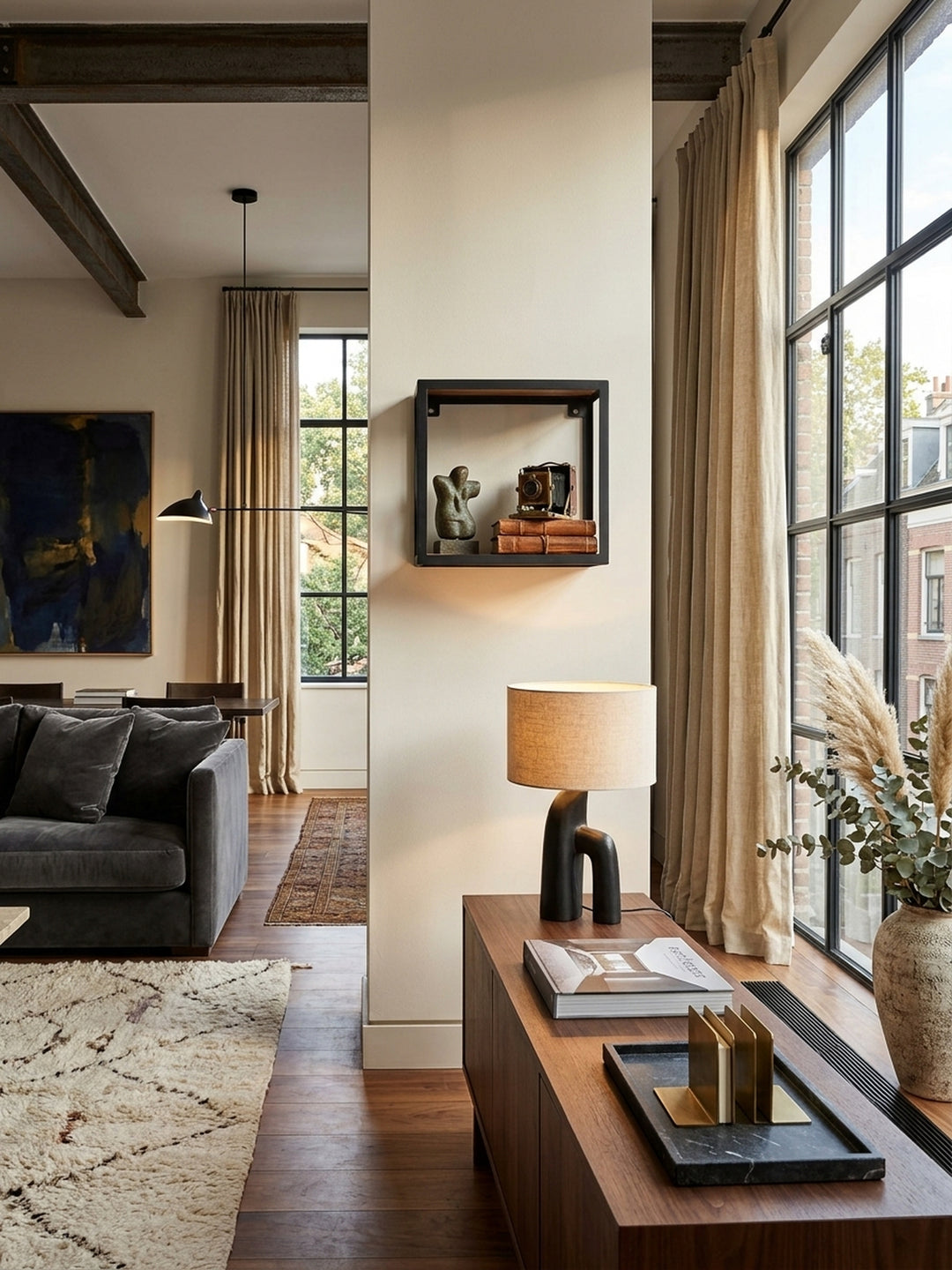Quadratisches Wandregal aus Sheesham Massivholz und schwarzem Metall in einem luxuriösen Loft-Wohnzimmer. Das 35x35 cm kleine Industrial-Hängeregal präsentiert edle Bronzeskulpturen._