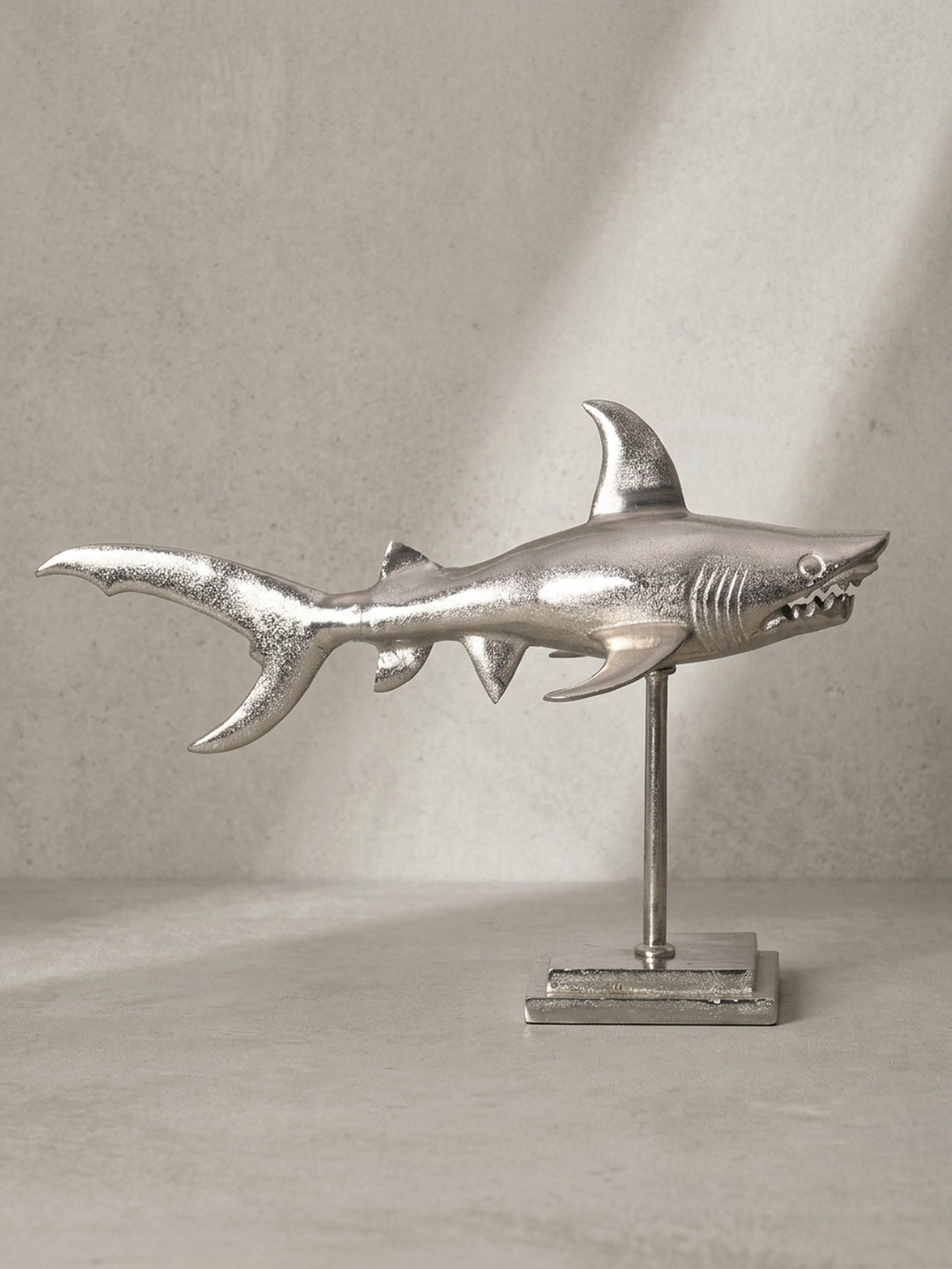 Übersicht der gesamten Wohndeko-Figur des Hais aus Aluminium, die das Zusammenspiel von Skulptur, Stab und massivem Sockel als Designobjekt veranschaulicht._