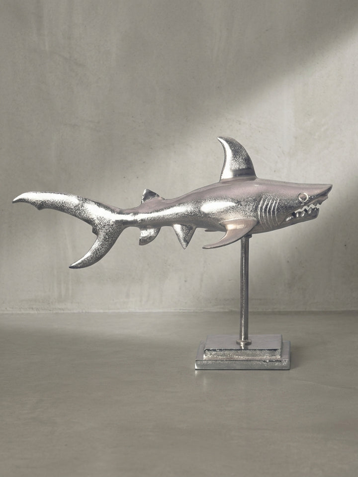Freigestellte Ansicht der eleganten Dekofigur eines Hais aus massivem Aluminium in Silber, die seine dynamische Silhouette auf dem Sockel zeigt._