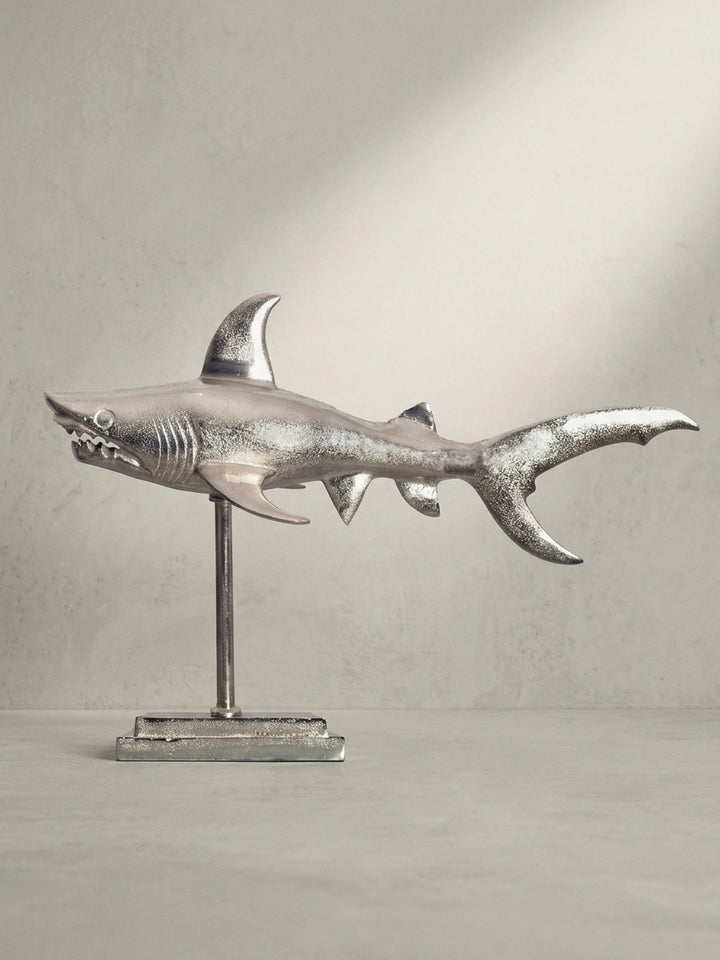 Moderne maritime Dekoration: Die Hai-Figur aus silbernem Metall in einer schrägen 3/4-Ansicht, die die Tiefe und die detaillierte Ausarbeitung der Flossen betont._