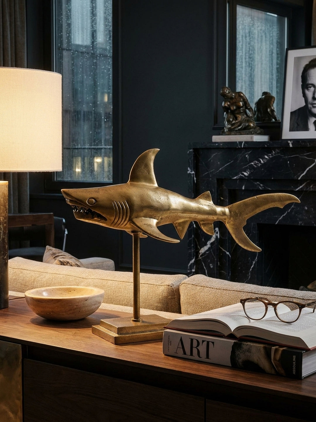 Einrichtungsdetail mit der goldenen Haifigur auf einem Regal, daneben eine minimalistische Vase und ein Stapel Bücher, die eine elegante, maritime Atmosphäre schaffen._