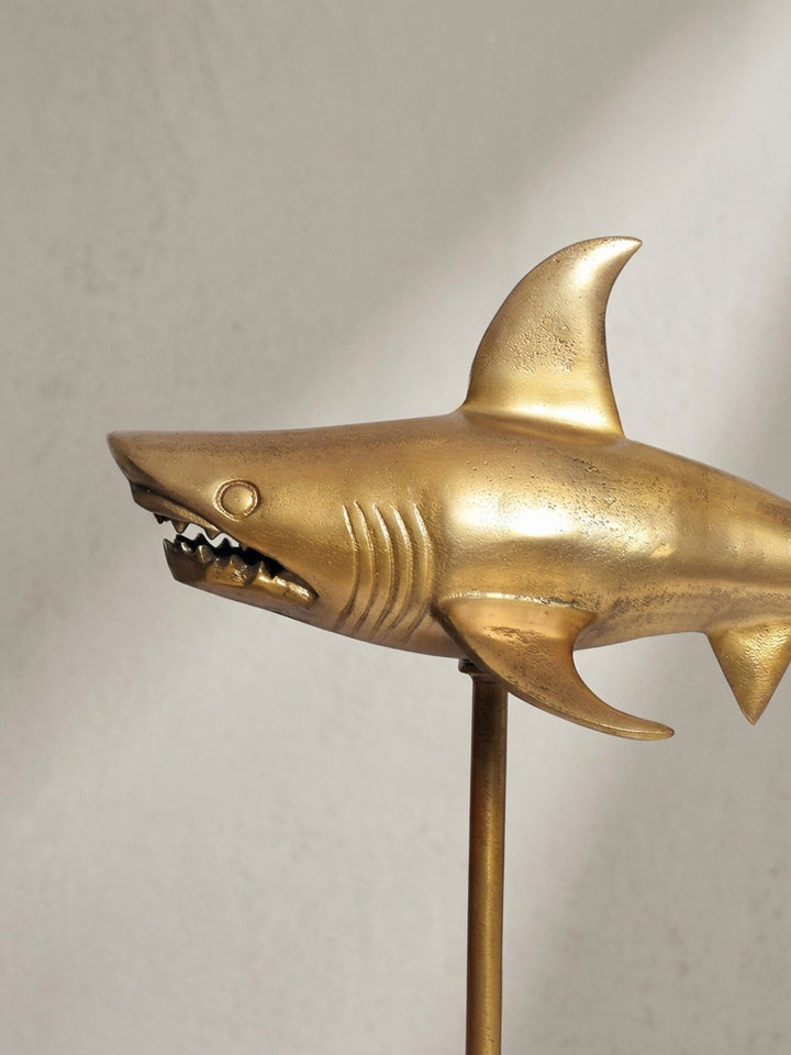 Alternative Perspektive auf die goldene Hai-Skulptur, die den dynamischen Charakter und die plastische Form des maritimen Wohnaccessoires betont._