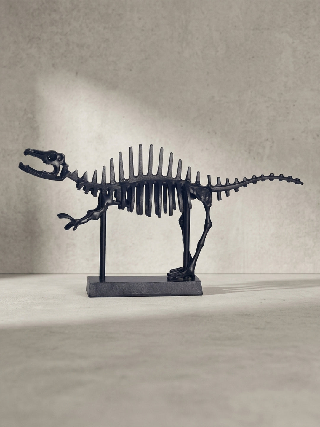 Dreiviertel-Ansicht der schwarzen Dinosaurier-Statue aus massivem Metall mit detailliert ausgearbeitetem Schädel und filigranem Knochenbau_