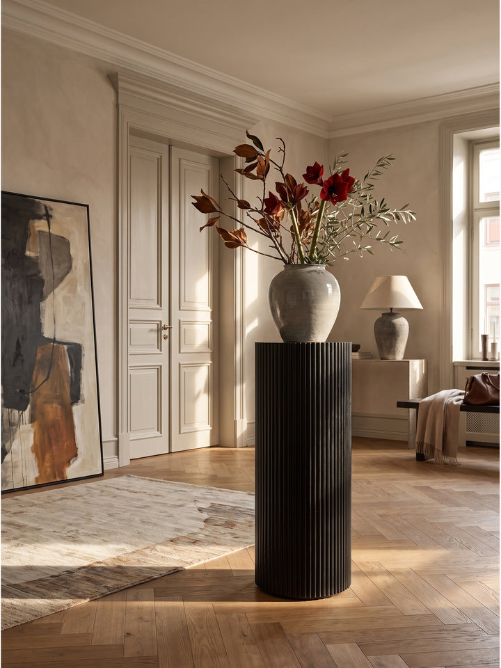 Schwarze Dekosäule aus massivem Akazienholz 30x30x80 cm als eleganter Blickfang im klassisch modernen Flur vor einer hellen Stuckwand_