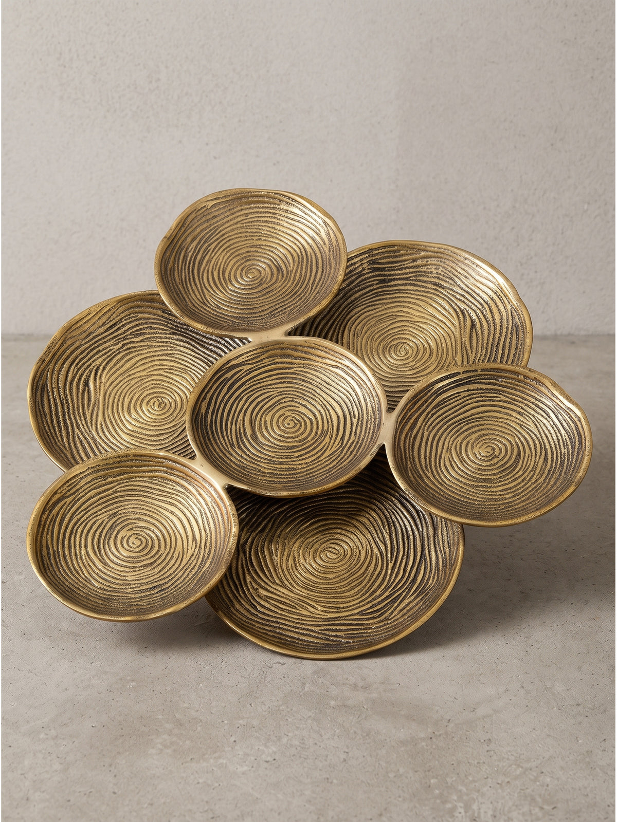 Frontalansicht der runden 44cm Dekoschale aus Aluminium in Gold mit strukturiertem Spiraldesign und sieben verbundenen Elementen_