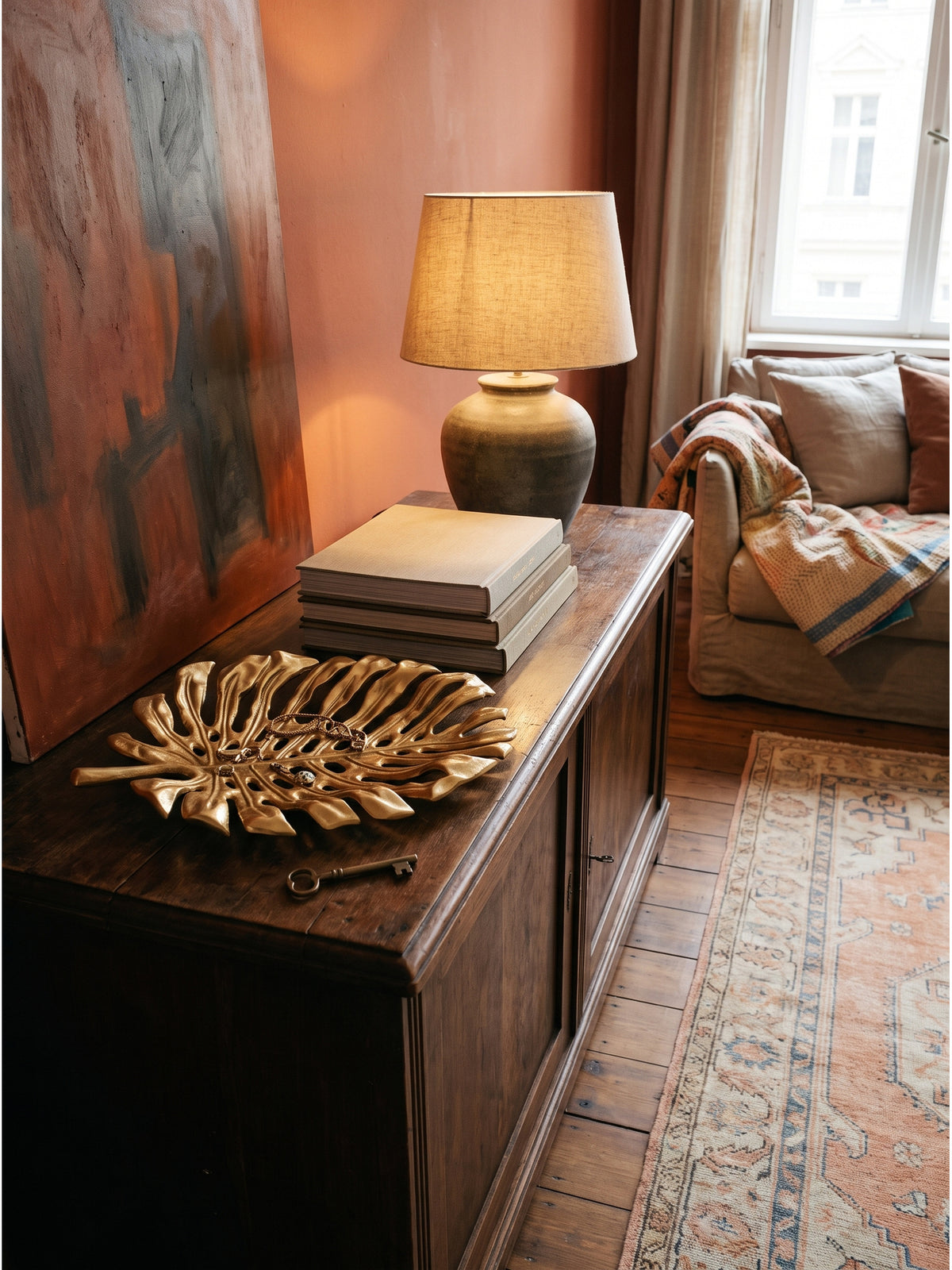 Elegante Flurgestaltung mit der goldenen Dekoschale auf einem Nussbaum-Sideboard im warmen Licht einer Keramik-Tischlampe_