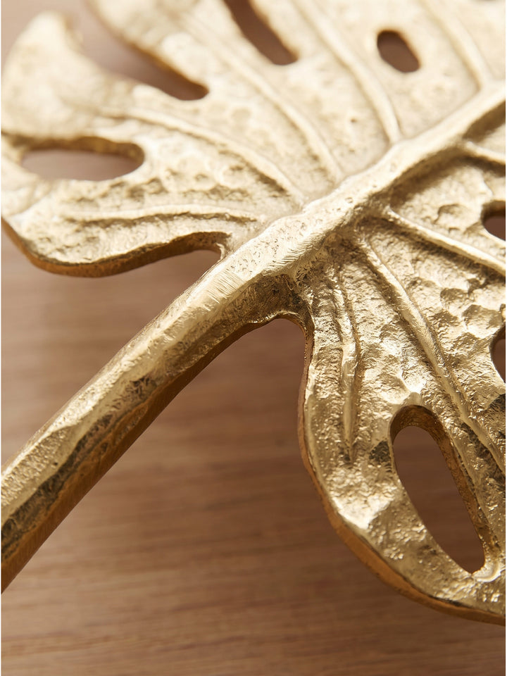 Detailaufnahme der handgefertigten Struktur der Aluminium Dekoschale in Gold mit floralem Muster auf Eichenholz_