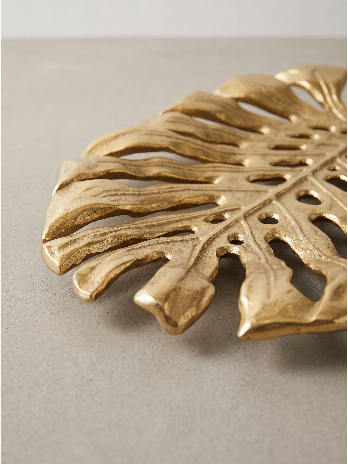 Florale Dekoschale aus Aluminium in strahlendem Gold als perfektes Einzelstück für den Wohnbereich auf weißem Grund_
