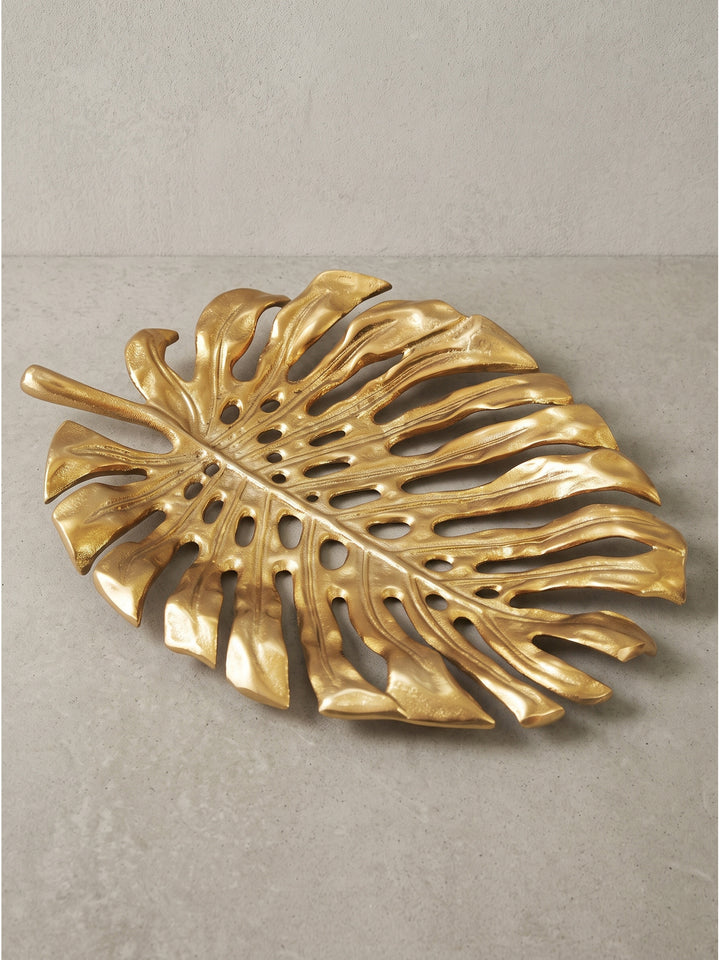 Nahaufnahme der strukturierten Oberfläche der goldenen Monstera Dekoschale aus robustem Aluminium im Studio_