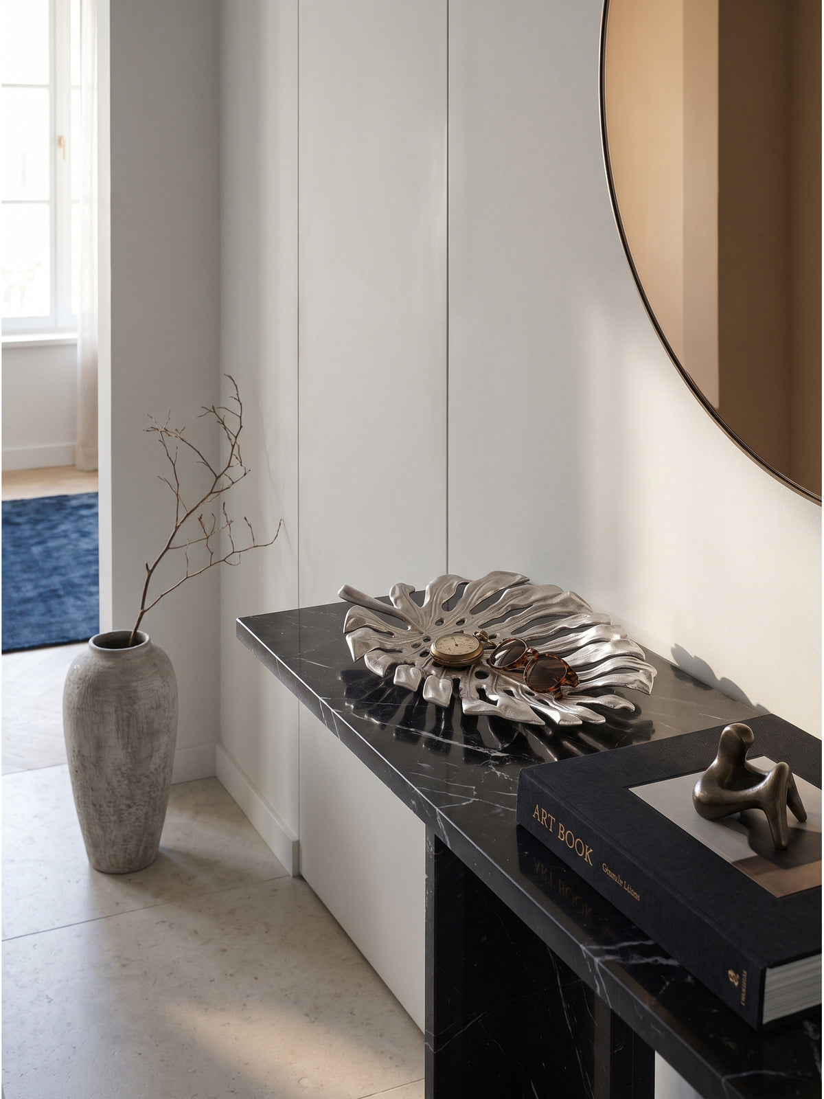 Dekoteller Blatt Design Silber arrangiert mit einer skulpturalen Keramikvase und trockenen Zweigen auf einer puristischen Steinplatte._