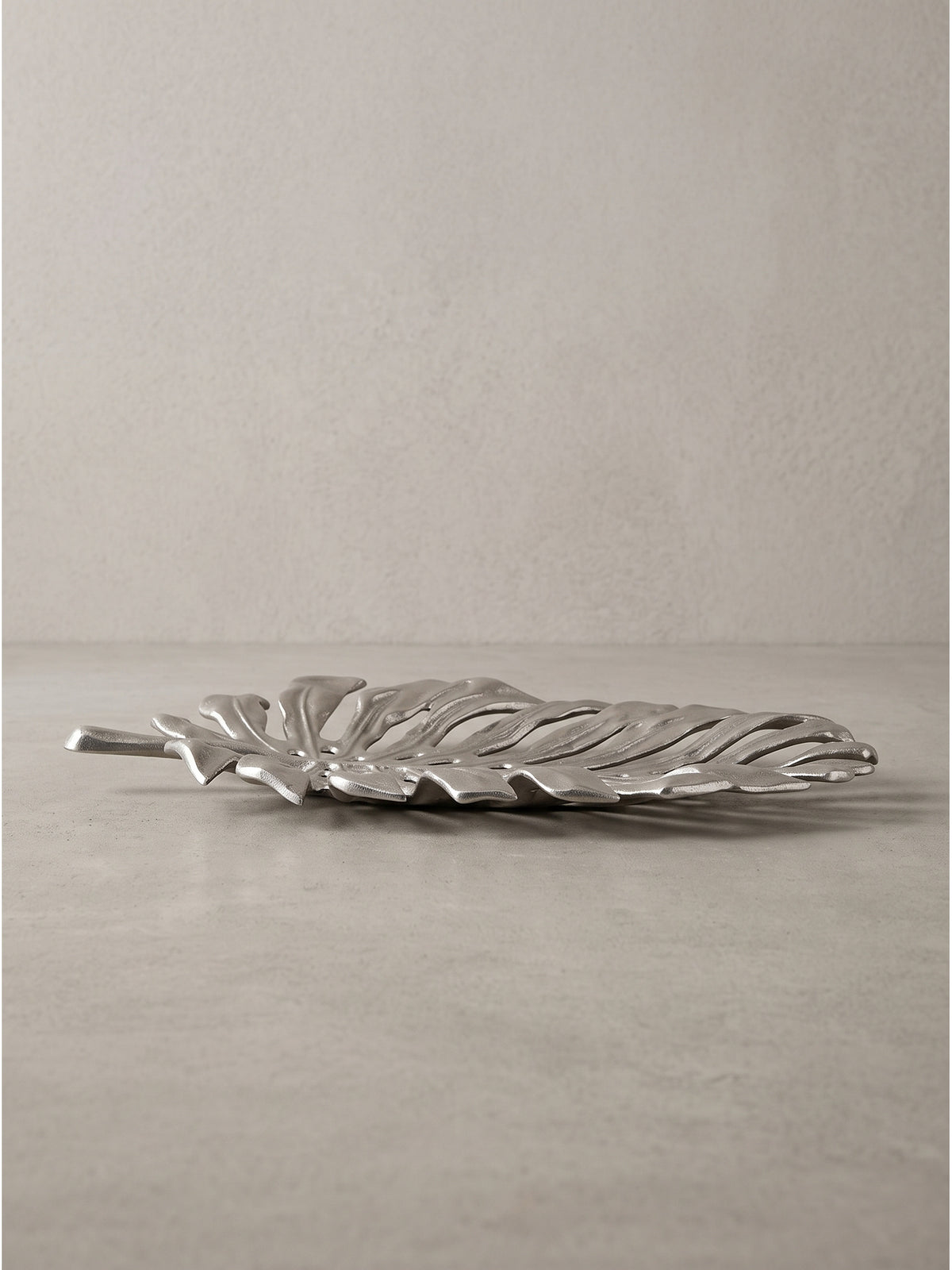 Flache Dekoschale aus Aluminium in der Seitenansicht mit besonderem Fokus auf den sanft geschwungenen massiven Stiel.