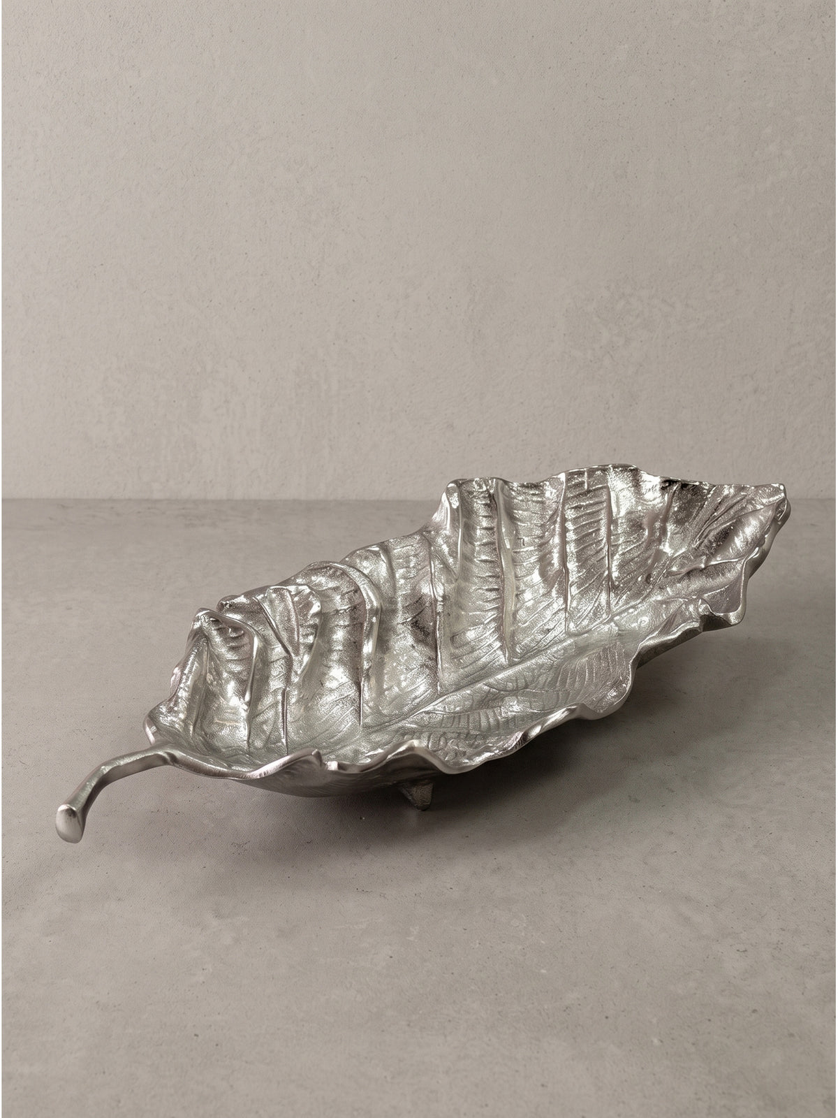 Detailaufnahme des geschwungenen Stiels der silbernen Dekoschale aus handgefertigtem Aluminium_