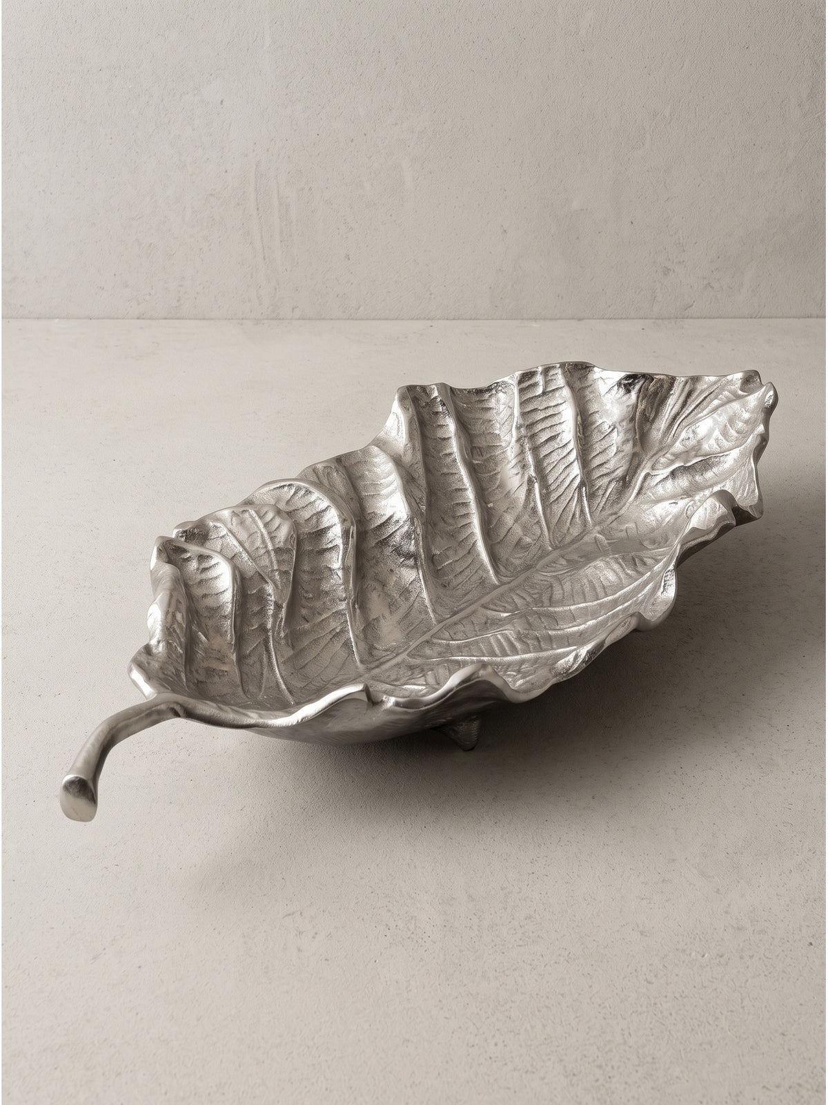 Dekoschale Blatt aus lackiertem Aluminium in Silber 67x27x11 cm mit geschwungenem Stiel in der Frontalansicht_