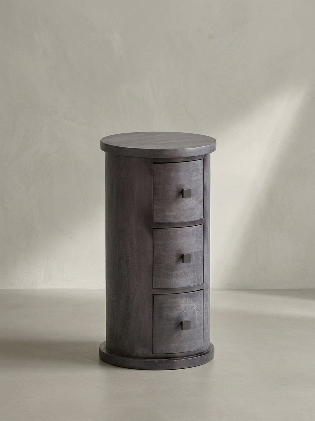 Gesamtansicht des Design-Beistellschranks aus Mangoholz, der durch seine runde Form und die schwarze Lackierung als zeitloses, massives Möbelstück wirkt._