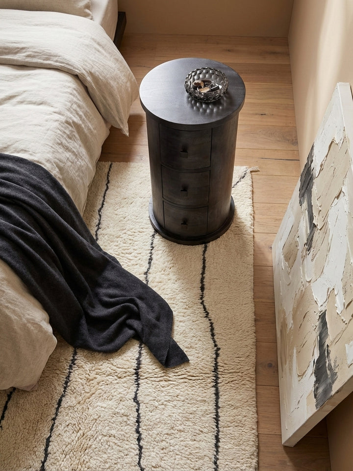 Von oben betrachtet fügt sich die runde Mini-Kommode harmonisch neben dem Bett ein und bietet eine elegante Ablagefläche aus schwarzem Mangoholz im Schlafzimmer._
