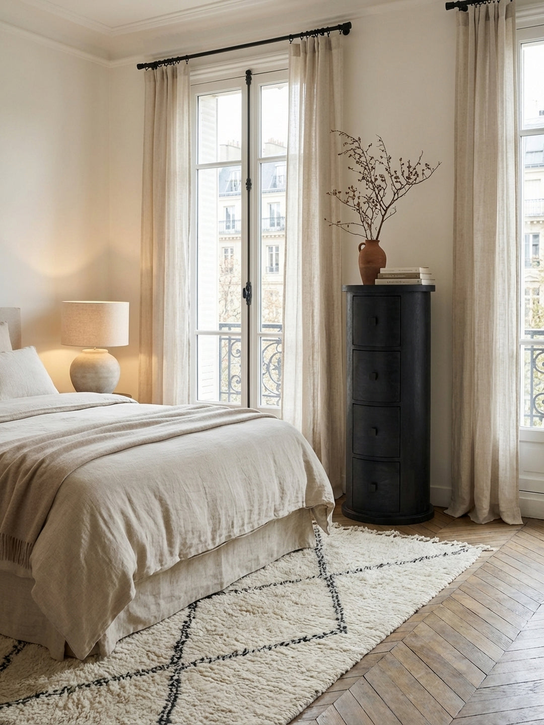 Die schmale schwarze Kommode aus Mangoholz als eleganter Nachttisch-Ersatz neben einem modernen Bett, der schmalen Stauraum im Schlafzimmer bietet._
