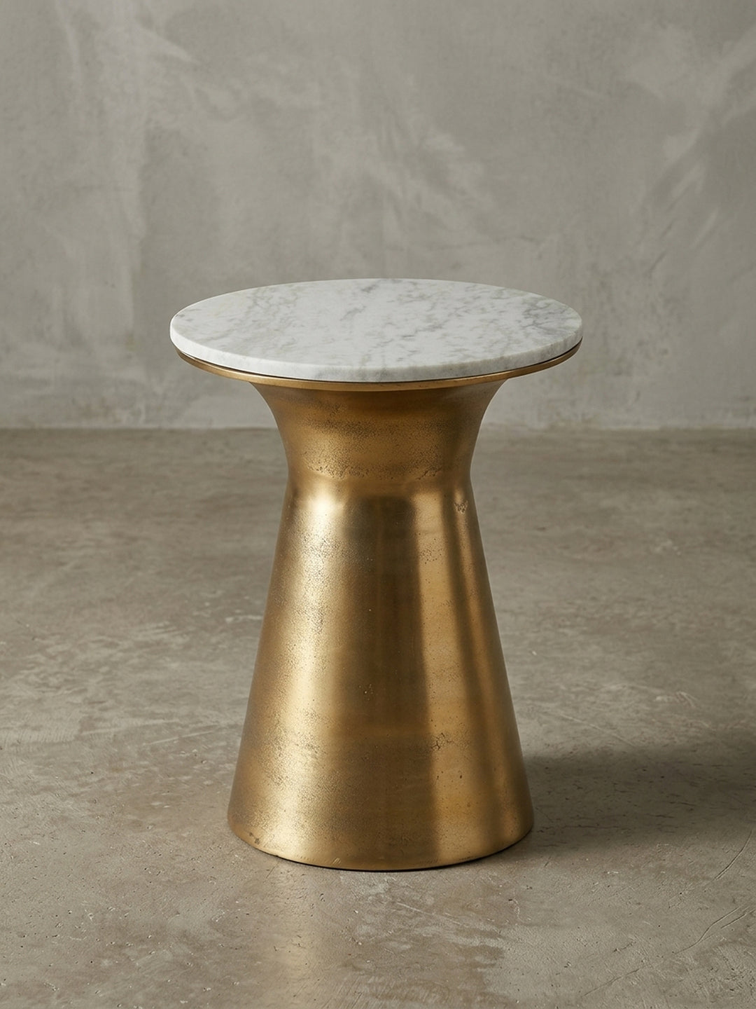 Design-Anstelltisch in der 3/4-Ansicht, die die schlanke Silhouette des goldenen Standfußes und die natürlich gemaserte Marmor-Tischplatte von 35 cm zeigt._