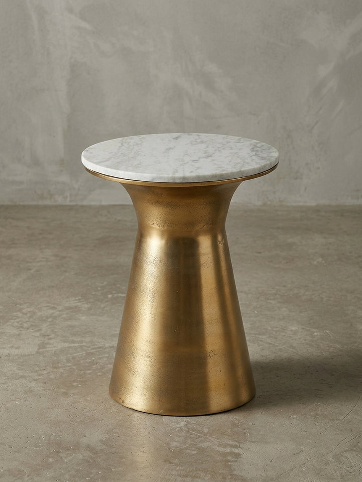 Design-Anstelltisch in der 3/4-Ansicht, die die schlanke Silhouette des goldenen Standfußes und die natürlich gemaserte Marmor-Tischplatte von 35 cm zeigt._