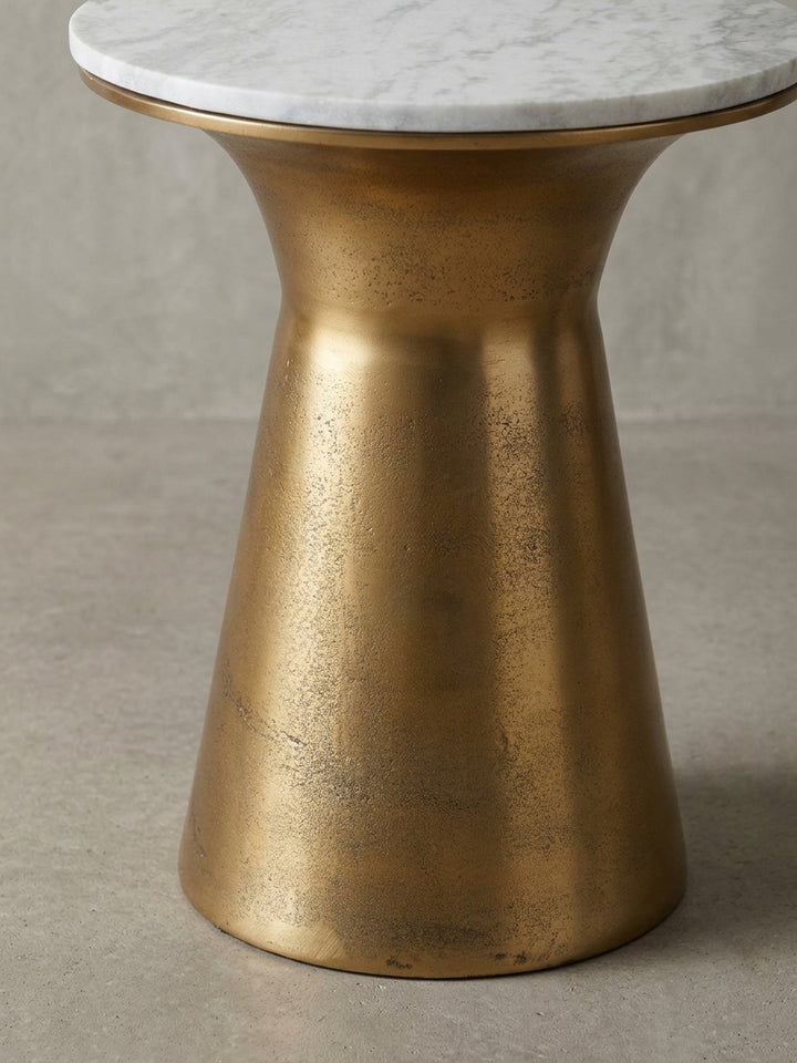 Makroaufnahme der Kante der weißen Marmor-Tischplatte, die in den goldenen Metallrahmen des Anstelltisches eingefasst ist, Materialdetail im Fokus._