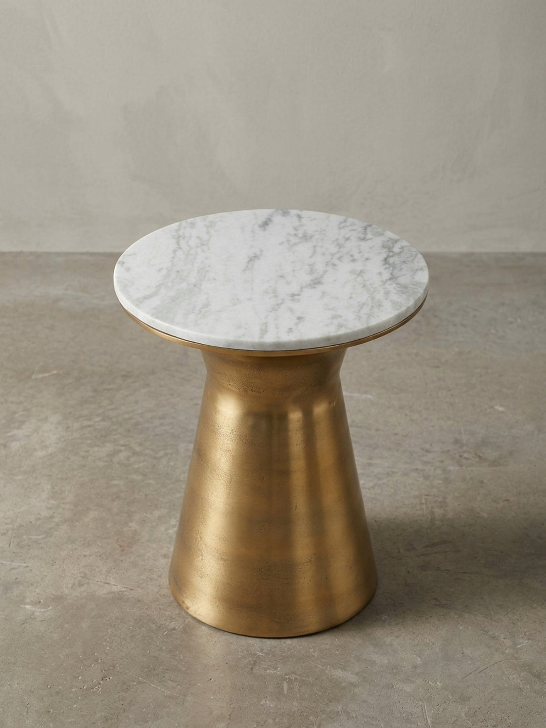 Alternativer Blickwinkel auf den runden Wohnzimmertisch, der die glatte Oberfläche der Marmorplatte und die matte Textur des goldenen Metalls betont._