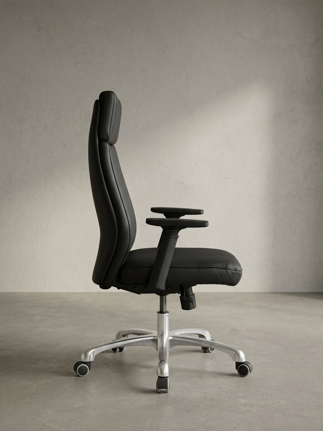Rückansicht des eleganten Schreibtischstuhls aus Echtleder, die die klare Linienführung und die solide Mechanik unter dem Sitz präsentiert._