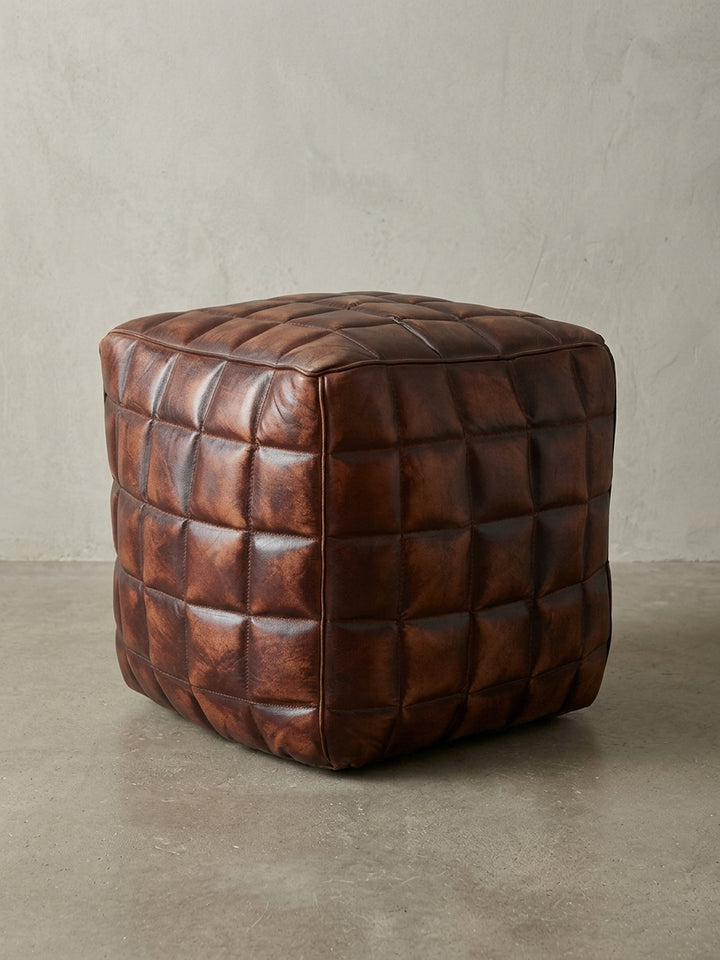 Frontalansicht des quadratischen Polsterhockers aus braunem Echtleder vor weißem Hintergrund, der die kompakten Maße von 39x39x41 cm und das symmetrische Design betont._