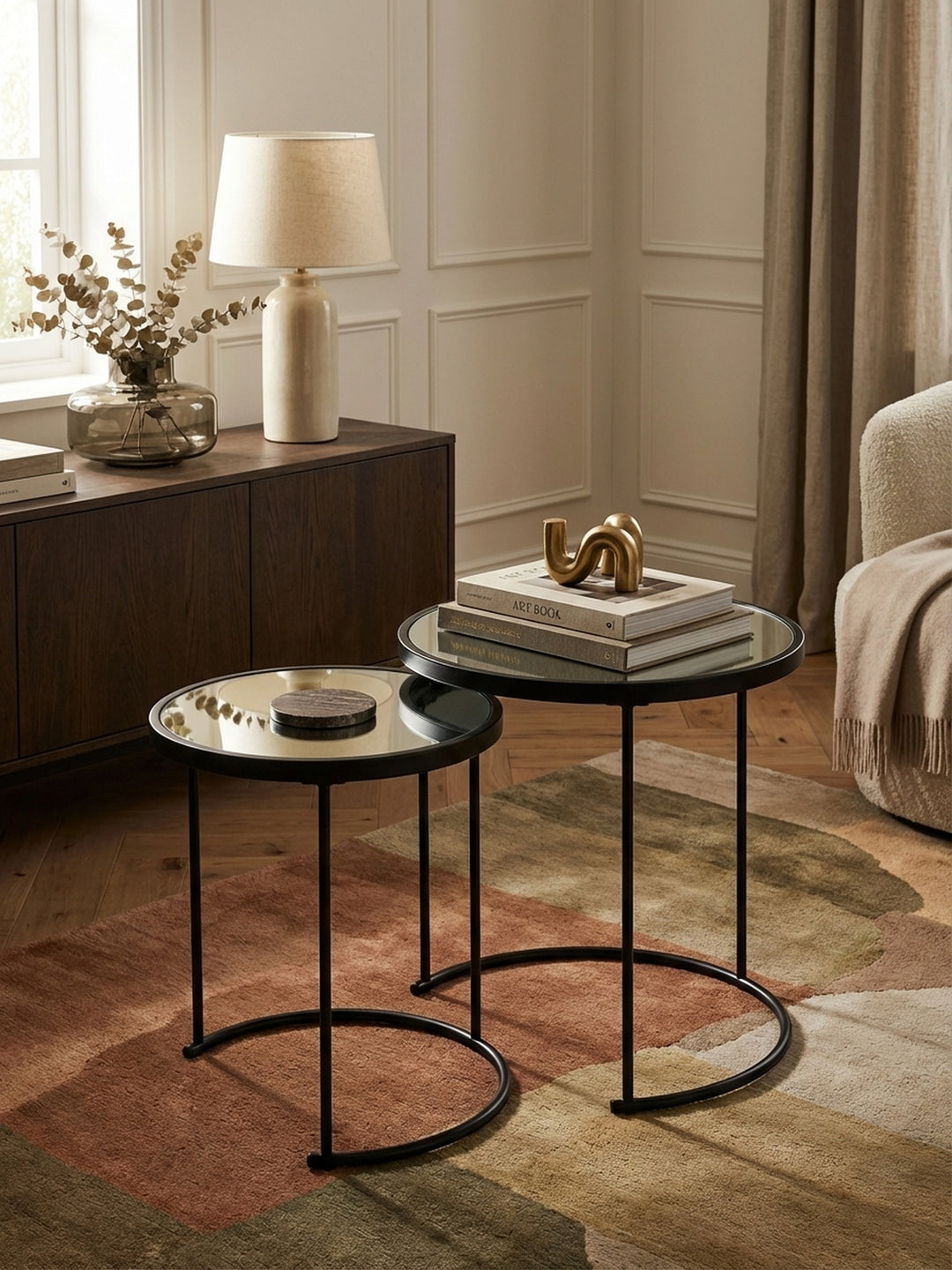 Runder Beistelltisch-Set von oben gesehen, das die verspiegelten Glasplatten und das platzsparende Nesting-Design im Zusammenspiel mit dem Wohnzimmer-Ambiente zeigt._