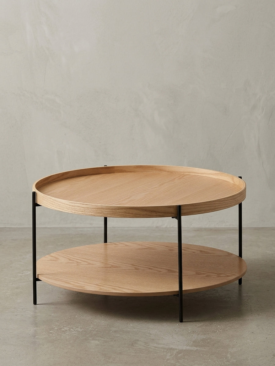 Moderner runder Couchtisch mit zwei Ebenen aus Eichenholz Furnier und schwarzem Metallgestell, freigestellt vor weißem Hintergrund._