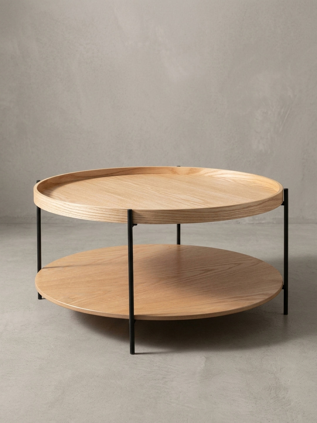 Sofatisch Eiche in 78 cm Durchmesser aus einer 3/4-Perspektive, die die filigrane Konstruktion der drei Stahlbeine hervorhebt._