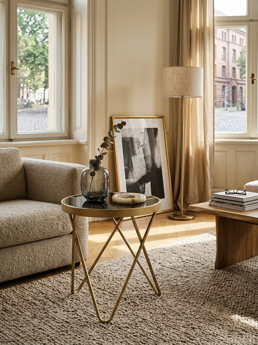 Draufsicht auf den runden schwarzen Couchtisch mit spiegelnder Glasplatte in einer stilvollen Lounge. Die 42x42 cm große Fläche bietet idealen Platz für edle Bildbände und Deko._