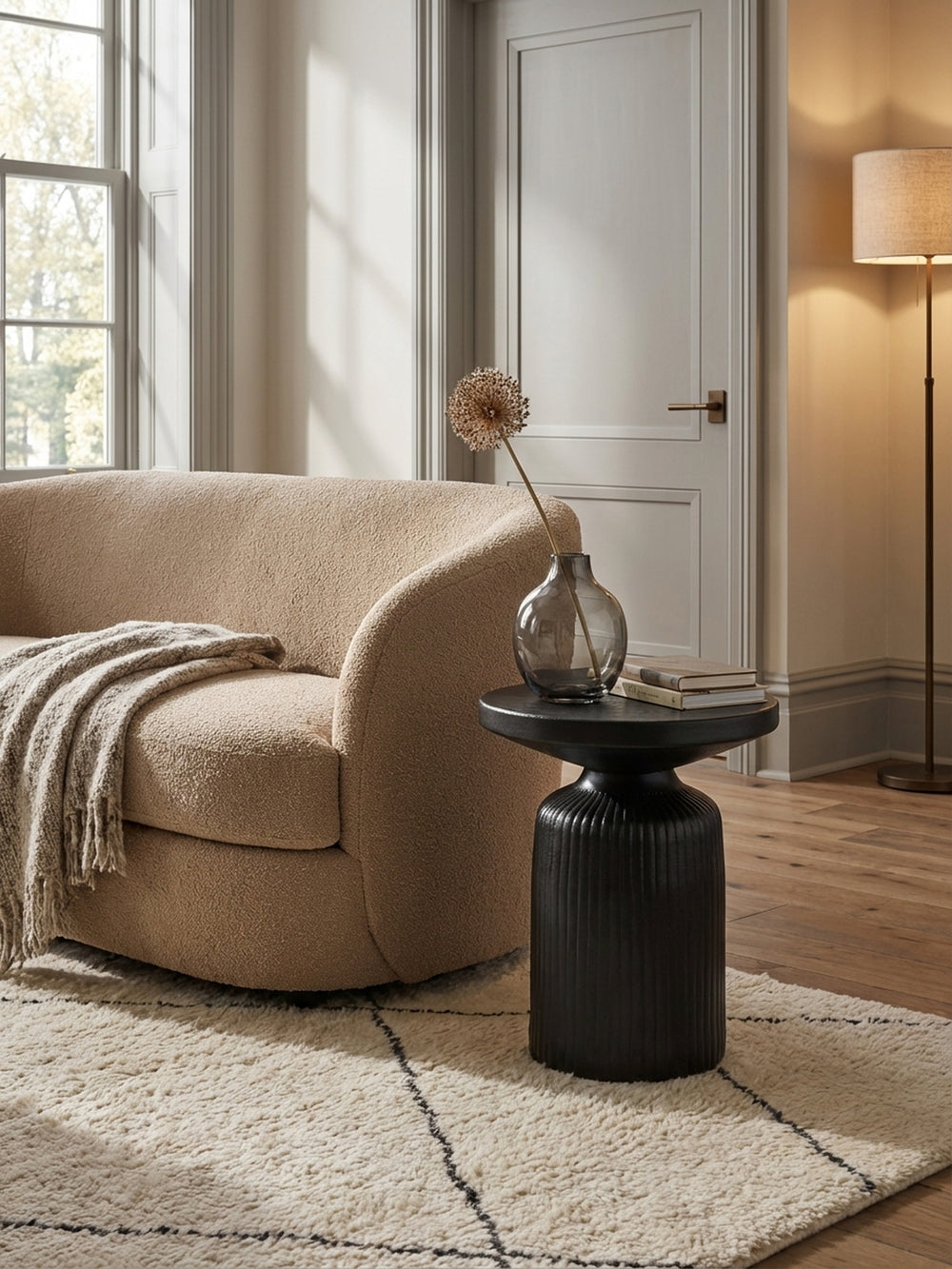 Der runde Sofatisch in Schwarz als stilvoller Akzent neben einer hellen Couch und einem warmen Teppich im organisch-modernen Interieur._