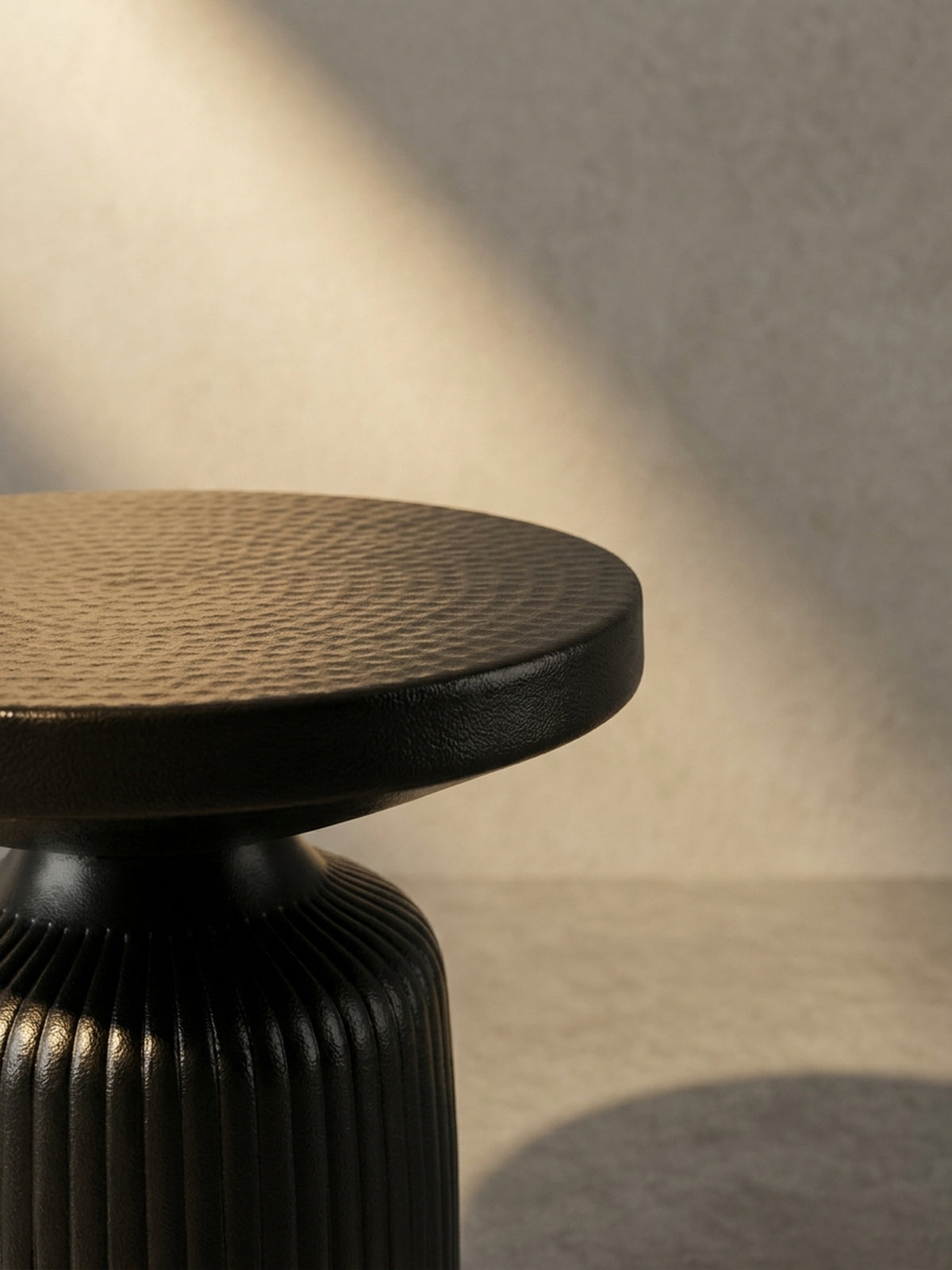 Alternativ-Perspektive des schwarzen Design-Beistelltisches, die das Zusammenspiel von glatter Kante und texturierter Oberfläche verdeutlicht._