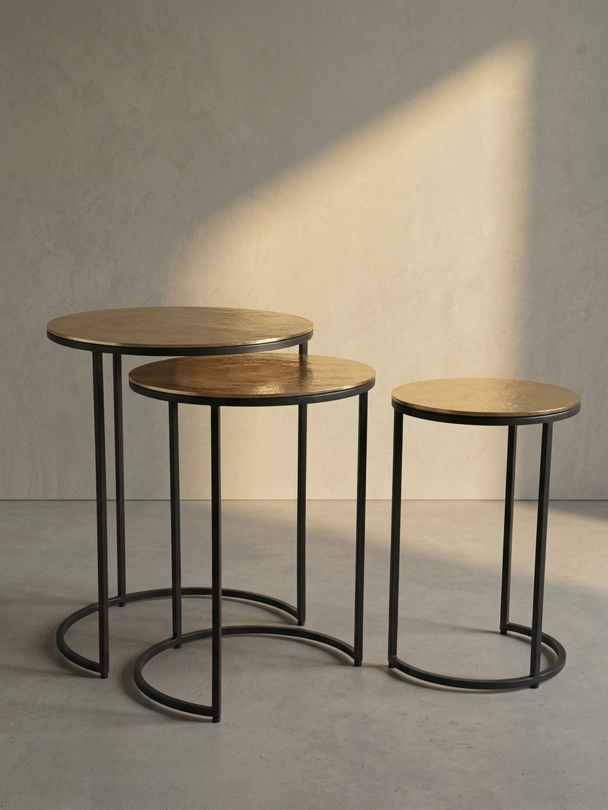 Schräge 3/4-Ansicht des dreiteiligen Satztisches, die die elegante Form des schwarzen Metallgestells und die goldenen Platten hervorhebt.