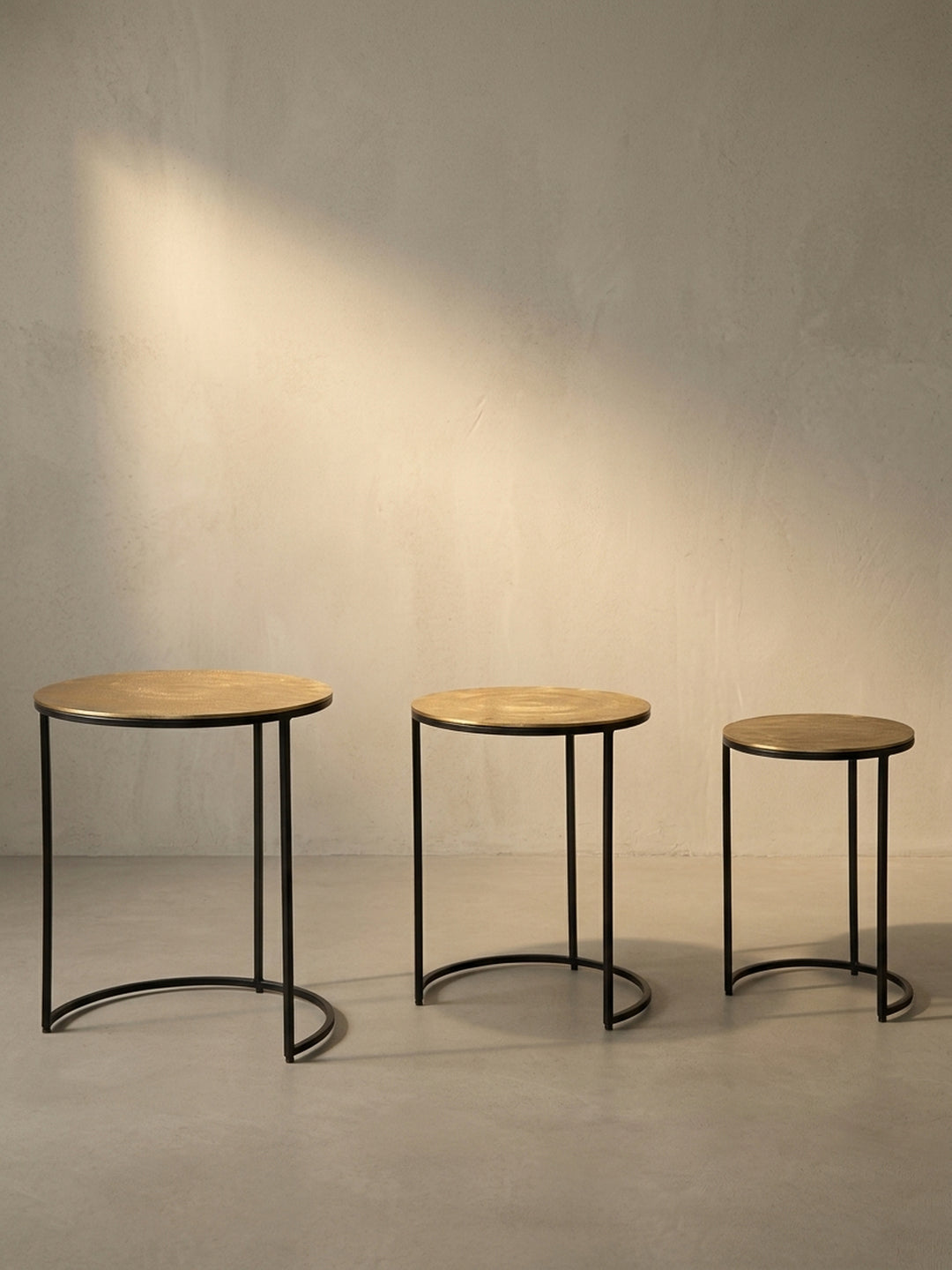 Gesamtüberblick über das Design des Satztisches, der die Kombination aus runden, goldenen Aluminiumplatten und grafischen schwarzen Metallgestellen zusammenfasst._