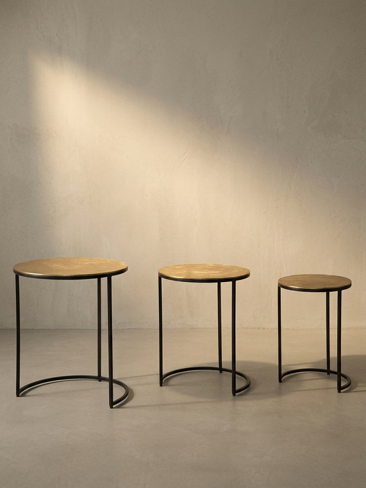 Gesamtüberblick über das Design des Satztisches, der die Kombination aus runden, goldenen Aluminiumplatten und grafischen schwarzen Metallgestellen zusammenfasst._