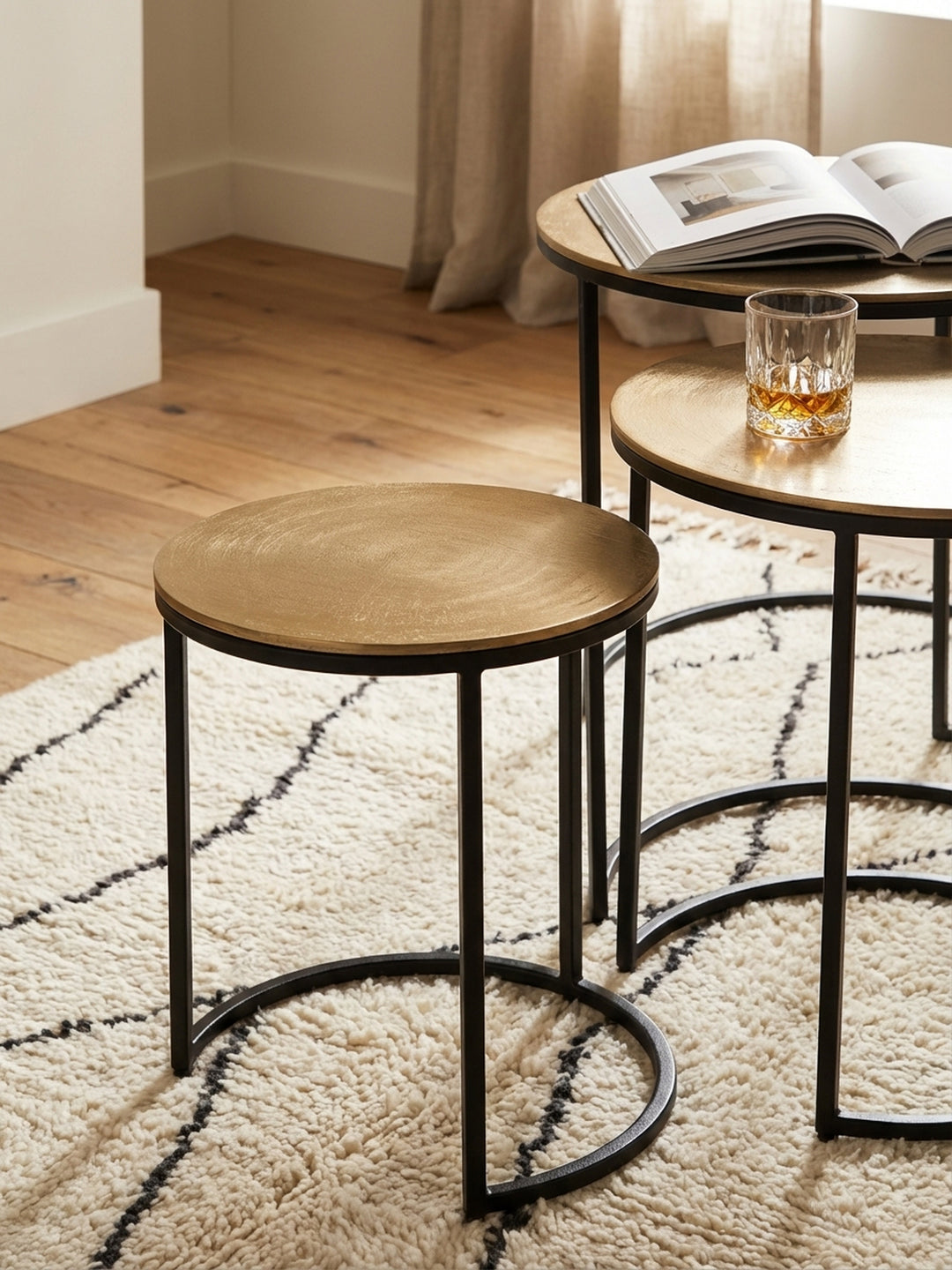 Detailaufnahme der texturierten, goldfarbenen Aluminium-Tischplatte eines runden Design-Beistelltisches, die das Licht sanft reflektiert._