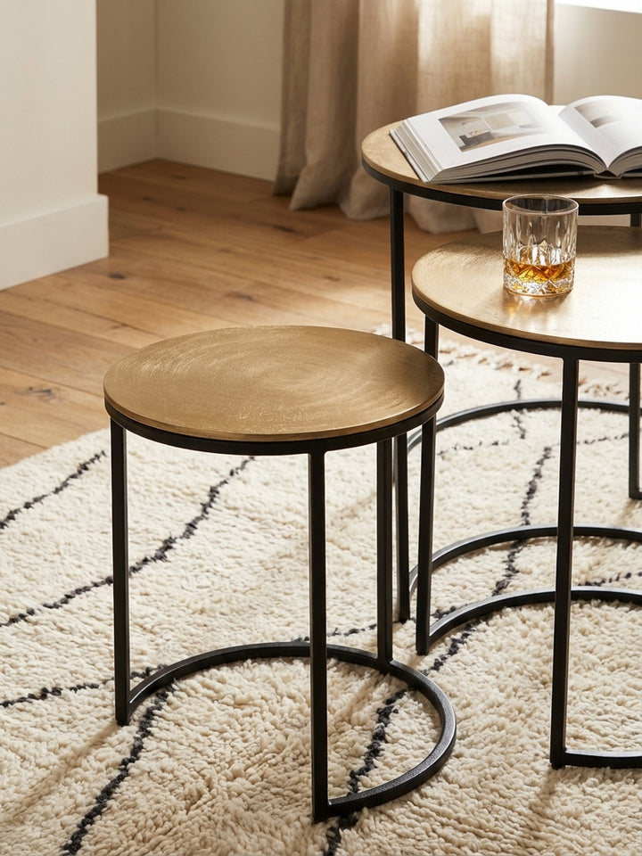 Detailaufnahme der texturierten, goldfarbenen Aluminium-Tischplatte eines runden Design-Beistelltisches, die das Licht sanft reflektiert._