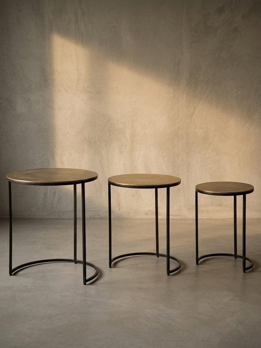 Freigestellte Ansicht des kompletten Beistelltisch-Sets in Gold und Schwarz, das die drei unterschiedlichen Größen deutlich zeigt._