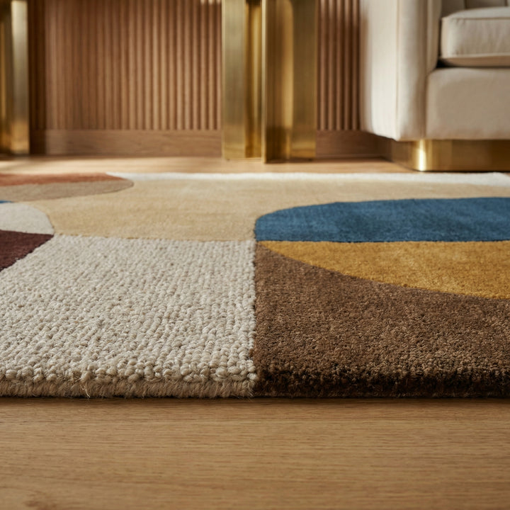 Ein moderner Teppich mit großen, bunten Kreisen und Formen liegt auf einem hellen Holzboden_