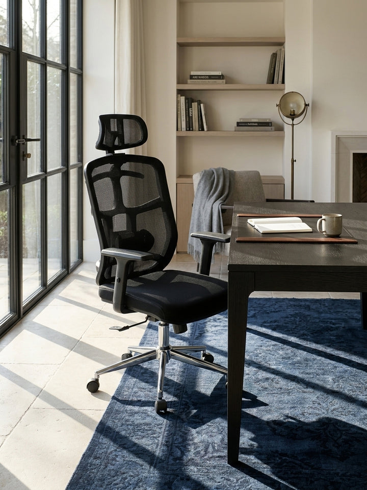 Der funktionale Stoff-Schreibtischsessel ergänzt sich hervorragend mit einem dunklen Holzregal vor einer fein strukturierten Gipswand im luxuriös eingerichteten Home-Office._