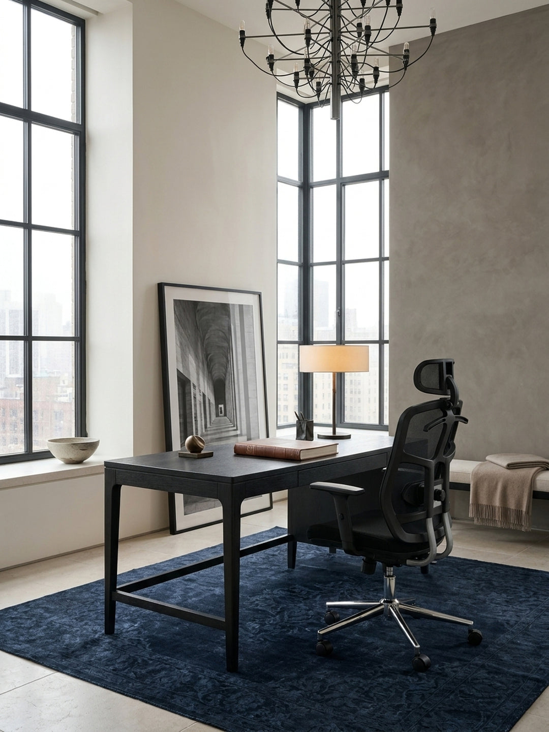 Aus der Vogelperspektive betrachtet fügt sich der schwarze Schreibtischstuhl mit seinem verchromten Fußkreuz perfekt auf den anthrazitfarbenen Teppich im modernen Arbeitszimmer ein._
