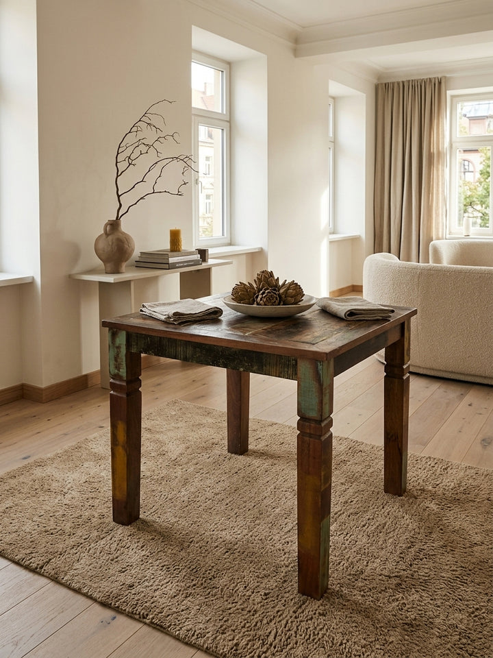 Aufsicht auf den kleinen 80x80 Esszimmertisch aus Mangoholz. Die bunte Maserung und der Used Look des quadratischen Küchentisches kommen auf dem hellen Teppich zur Geltung._