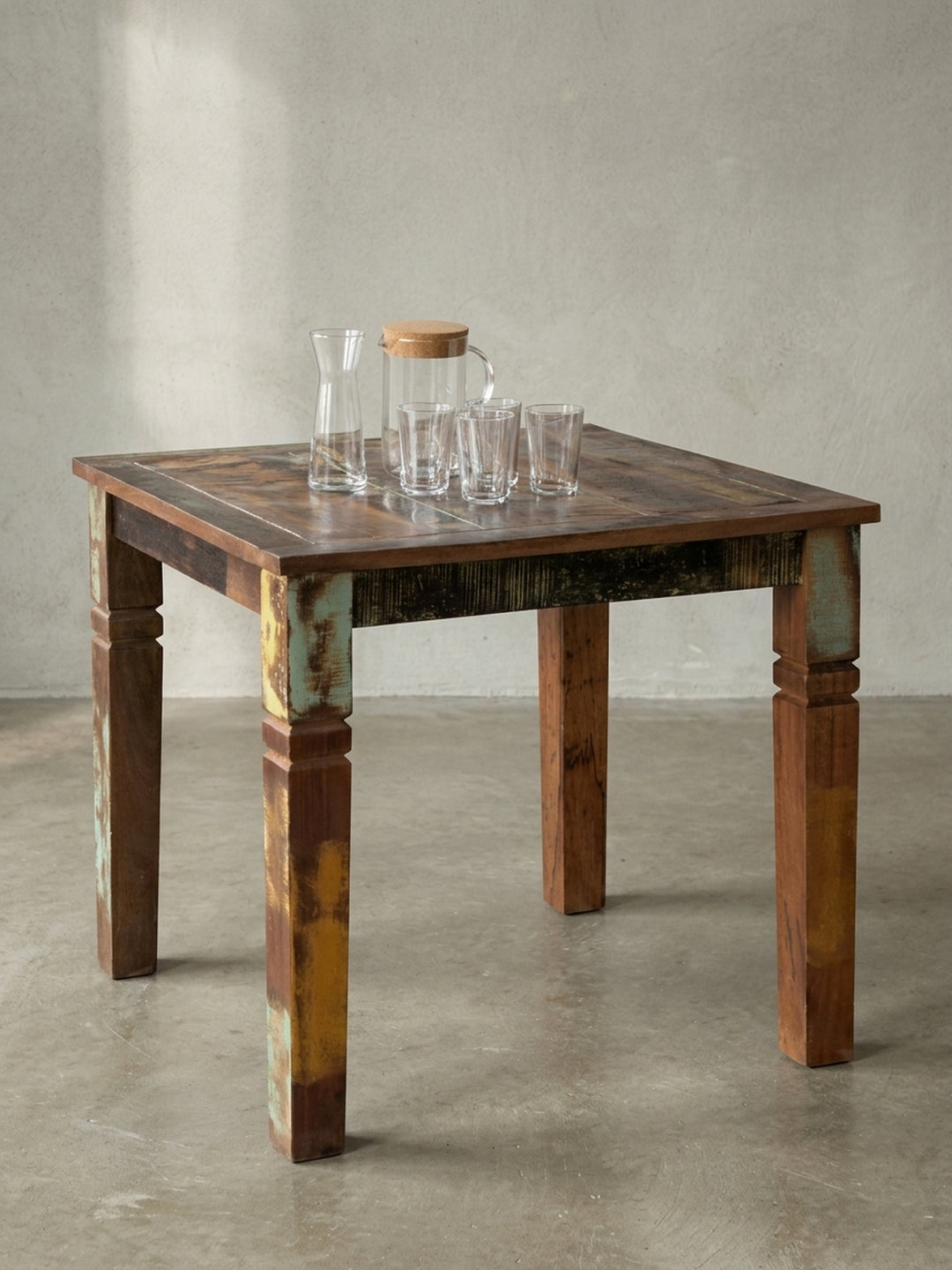 Schrägansicht des quadratischen Esszimmertisches für 4 Personen. Die stabile Konstruktion des Massivholztisches im Shabby Chic Stil zeigt charakteristische Farbabrieb-Details._