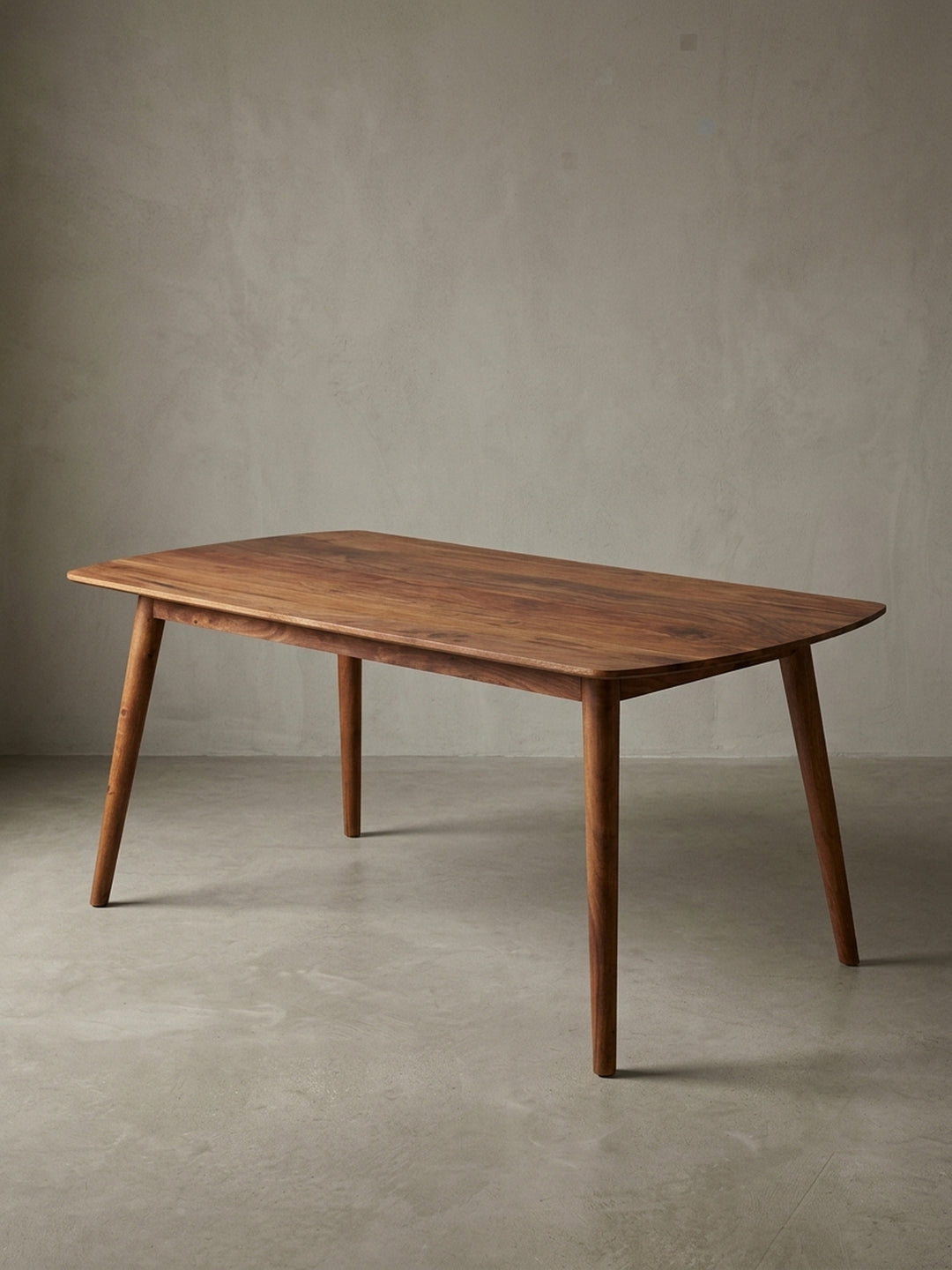 Frontalansicht des freistehenden Esszimmertisches aus massivem Sheeshamholz. Die sanft abgerundete Tischplatte 120x60 cm ruht elegant auf vier schräg ausgestellten, runden Holzbeinen._