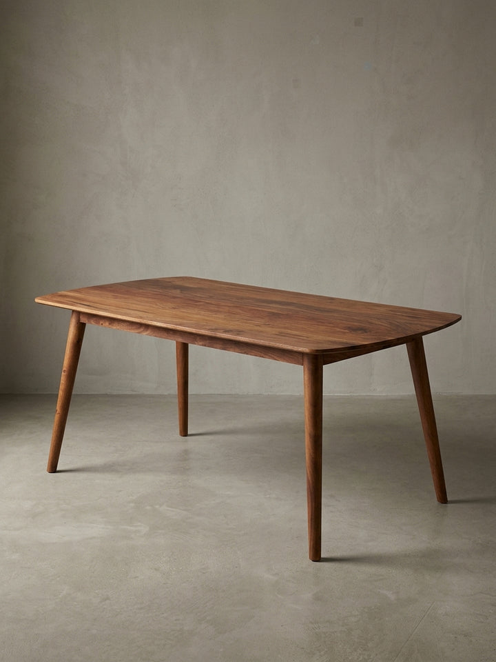 Frontalansicht des freistehenden Esszimmertisches aus massivem Sheeshamholz. Die sanft abgerundete Tischplatte 120x60 cm ruht elegant auf vier schräg ausgestellten, runden Holzbeinen._