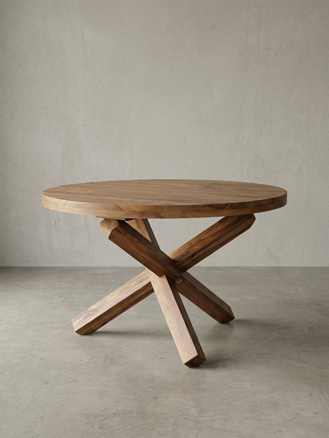 Frontansicht des runden Landhaus Esstisches BOHA. Die markanten gekreuzten Massivholz-Beine und die 120cm breite Tischplatte aus braunem Sheeshamholz wirken besonders stabil._
