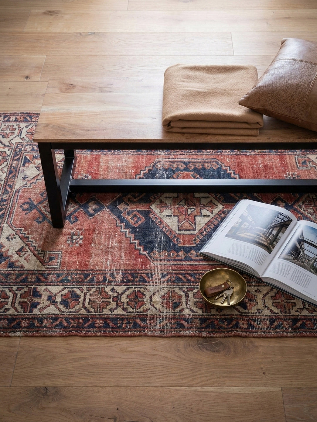 Draufsicht auf die massive Holzbank am Esstisch, arrangiert auf einem Vintage-Kilim-Teppich, zeigt die Sitzordnung im offenen Essbereich eines Lofts._