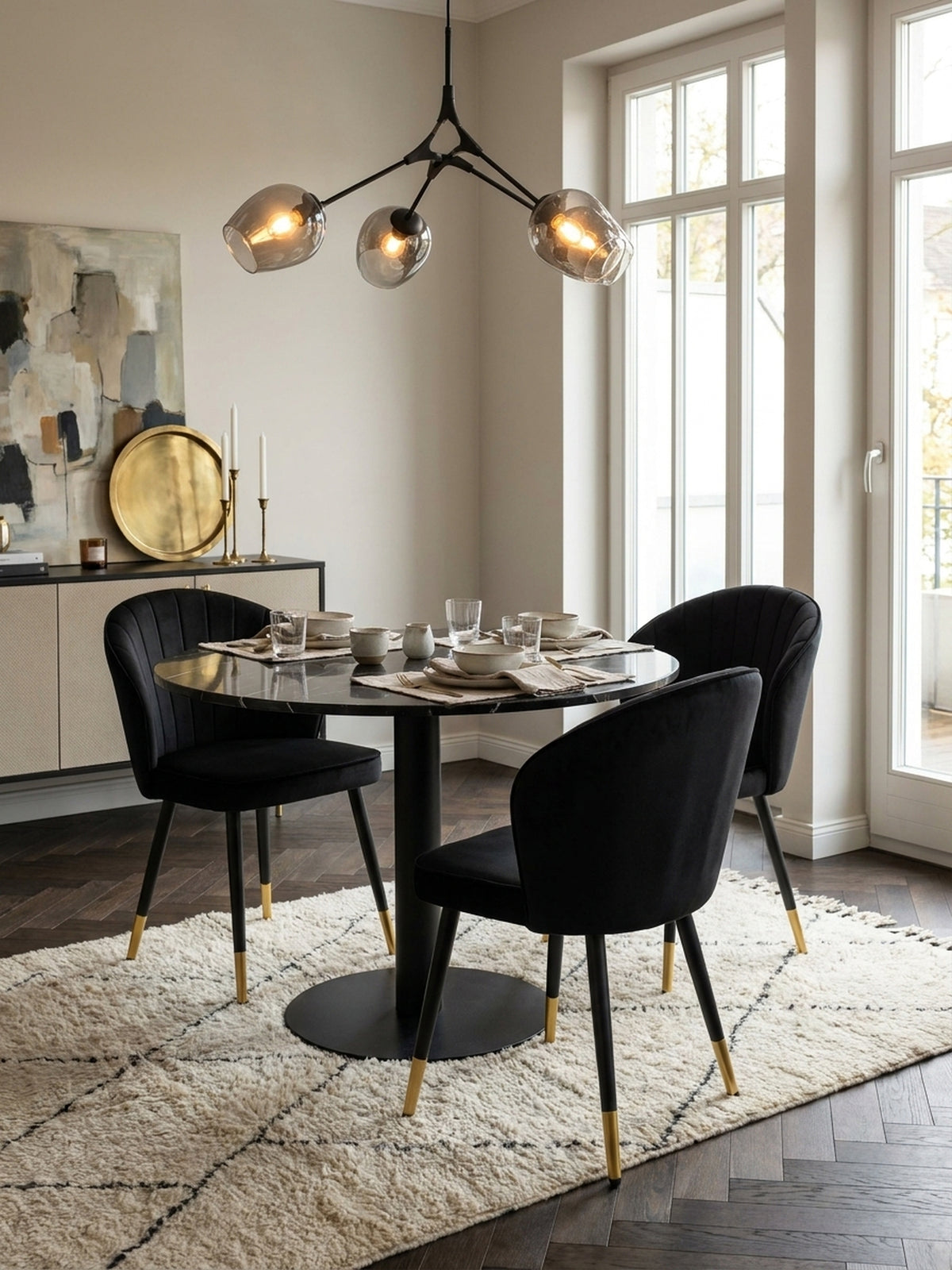 Zwei schwarze Esszimmerstühle aus Samt im stilvollen Set kombiniert mit einem massiven dunklen Holztisch vor einer weißen Wand mit klassischen Stuckdetails.