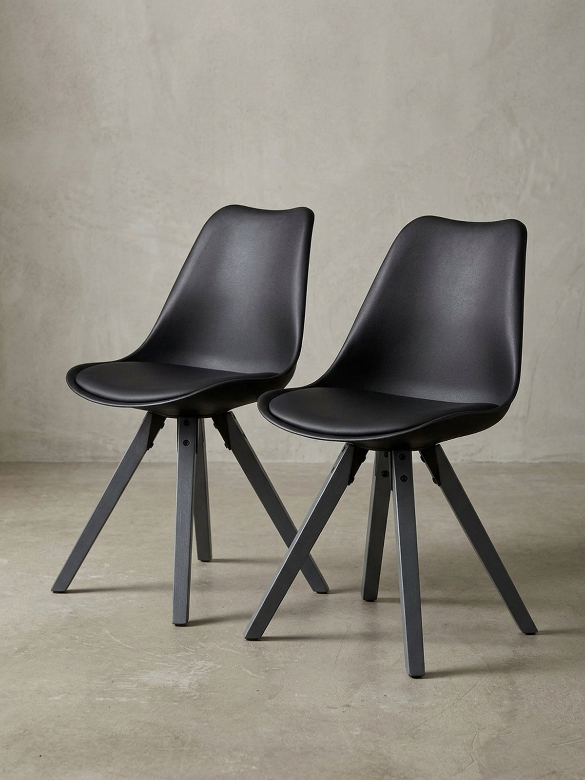 Frontansicht des schwarzen Retro-Esszimmerstuhls auf weißem Grund, zeigt die ergonomische Kunststoff-Sitzschale und die eleganten Holzbeine.